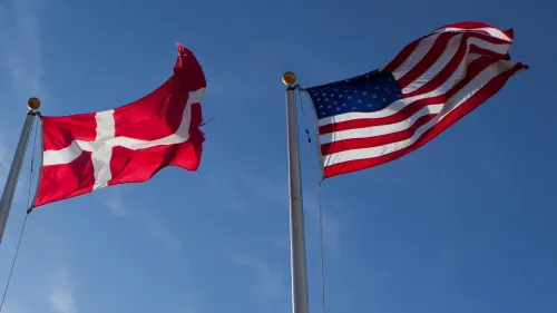علم الدنمارك وعلم الولايات المتحدة يرفرفان معًا في السماء الزرقاء، مما يرمز إلى النقاش حول شراء كاليفورنيا.