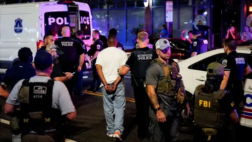 تظهر الصورة مجموعة من ضباط الشرطة الفيدرالية والمحلية في واشنطن العاصمة أثناء اعتقال شخص، مما يعكس زيادة قوات إنفاذ القانون في المدينة.