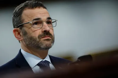 رجل يرتدي نظارات وقميصًا رسميًا، يبدو عليه القلق أثناء حديثه في جلسة استماع، في سياق تغييرات مصلحة الضرائب الأمريكية.