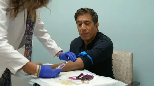 رجل يجلس في عيادة طبية أثناء سحب عينة دم، مع وجود عدة أنابيب اختبار ملونة على الطاولة، في سياق بحث حول الخرف.