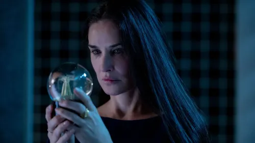 امرأة ذات شعر داكن طويل، تحمل كرة زجاجية في يدها، تعبر عن مشاعر عميقة في مشهد من فيلم "المادة" الذي يتناول قضايا كراهية النساء والتمييز.