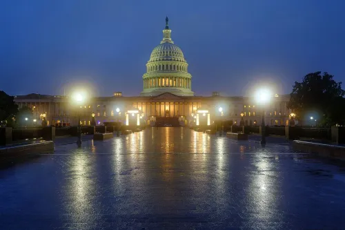 مبنى الكابيتول الأمريكي مضاء في الليل، مع انعكاسات الضوء على الرصيف الرطب، مما يعكس أهمية السياسة الأمريكية في الانتخابات المقبلة.