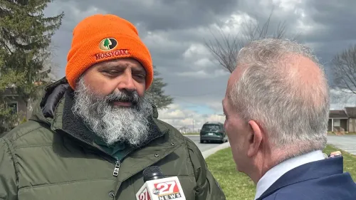 رجل ذو لحية وشعر رمادي يرتدي قبعة برتقالية يتحدث مع صحفي في منطقة ريفية، تعكس الصورة الأجواء السياسية في بنسلفانيا بعد فوز جيمس مالون.