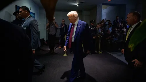 ترامب يسير في ممر مع حراسه، وسط حشد من الصحفيين، بعد حديث عن تخفيضات تمويل مشاريع الفيضانات في الولايات الزرقاء.