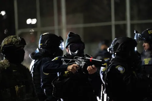 تظهر الصورة مجموعة من الضباط الفيدراليين يرتدون معدات تكتيكية، بعضهم يحمل أسلحة غير قاتلة، خلال احتجاجات في مينيابوليس ضد قوانين الهجرة.