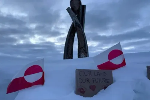 تمثال يرمز إلى الهوية الثقافية لغرينلاند، محاط بأعلام غرينلاند وعبارة "أرضنا مستقبلنا" مكتوبة على لافتة، تعبيرًا عن الرغبة في الاستقلال.