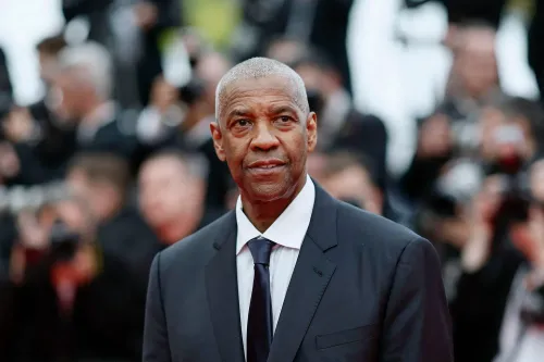 دينزل واشنطن في عرض رسمي، يرتدي بدلة أنيقة، وسط حشد من المصورين، مع التركيز على تعبيره الجاد أثناء مناقشة صناعة الأفلام.