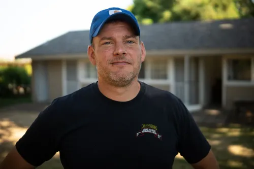 مزارع يقف أمام منزله، يعبّر عن قلقه حول نقص العمالة في حصاد الكرز، مما أدى إلى فقدان الإيرادات.