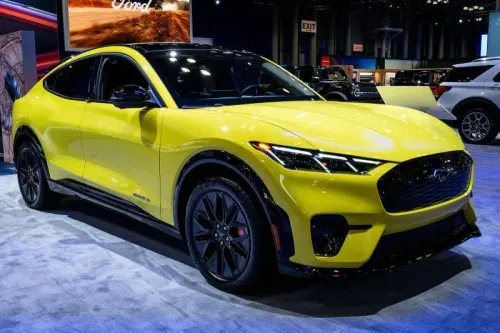 سيارة فورد كهربائية صفراء حديثة مع تصميم رياضي، معروضة في معرض للسيارات، تعكس التوجه نحو الابتكار في صناعة السيارات.