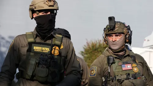 عملاء فيدراليون يرتدون زيًا عسكريًا، يتجولون في منطقة حضرية، مما يعكس تصعيد الأنشطة الأمنية في شيكاغو.
