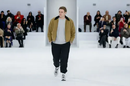 جوناثان أندرسون، مصمم الأزياء الجديد لدار ديور، يسير على منصة عرض الأزياء وسط جمهور من الحضور.