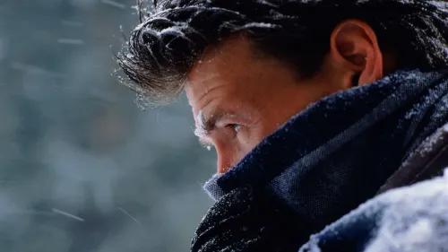 رجل يرتدي وشاحًا داكنًا في بيئة شتوية، مع تساقط الثلوج حوله، يعكس تأثير الطقس البارد على البشرة.