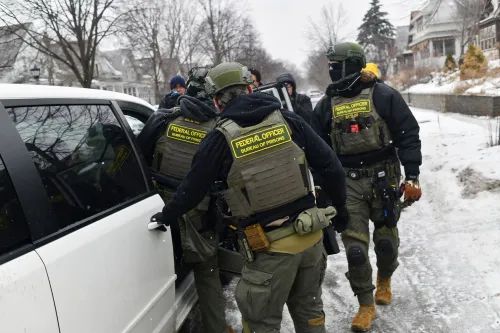 ضباط فيدراليون بزي تكتيكي يفتّشون سيارة في شارع ثلجي بمدينة Minneapolis ضمن عملية سرية لمراقبة نقابات عمالية ومنظمات تقدّمية.