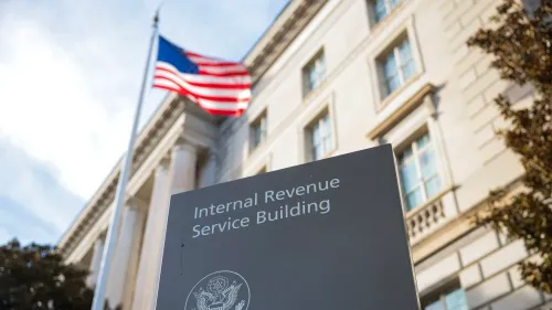 مبنى دائرة الإيرادات الداخلية في واشنطن، مع العلم الأمريكي يرفرف في الخلفية، يعكس زيارة فريق إدارة الكفاءة الحكومية لتقييم الوكالة.