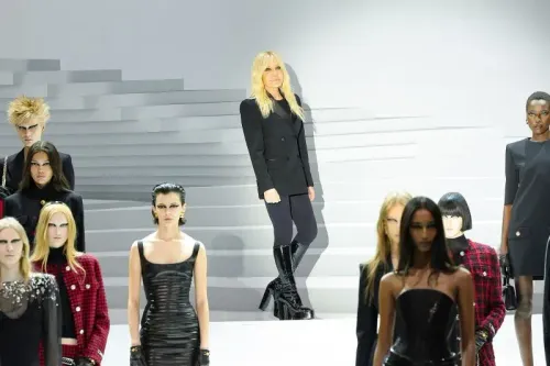 دوناتيلا فيرساتشي تقف بفخر خلف عارضات الأزياء خلال عرض أزياء فيرساتشي في ميلانو، مع لمسة من الأناقة والتميز.