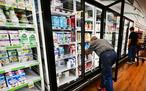 رجال يتسوقون في متجر، يختارون منتجات الألبان من الثلاجات، في سياق ارتفاع أسعار المواد الغذائية.