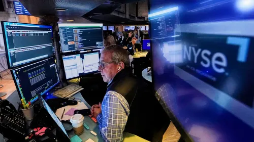 تاجر في سوق الأسهم يعمل أمام شاشات متعددة تعرض بيانات السوق، مع التركيز على نشاط التداول بعد تقرير الوظائف القوي.