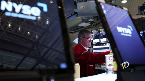 تاجر في بورصة نيويورك يقوم بمراقبة شاشات التداول، مع ظهور شعار NYSE، وسط أجواء من القلق بشأن تأثير التعريفات الجمركية على السوق.