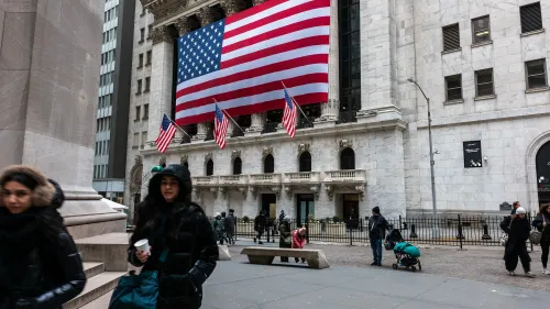 تظهر الصورة واجهة بورصة نيويورك مع علم الولايات المتحدة الكبير، بينما يتجول الناس في الشارع، مما يعكس حالة الأسواق المالية.