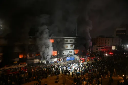 اندلع حريق هائل في جول بلازا بكاراتشي، حيث يتصاعد الدخان من المبنى بينما يتجمع رجال الإطفاء والجمهور في الأسفل.