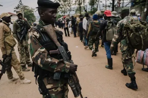 مقاتل يحمل سلاحًا، واقفًا أمام صف من الأشخاص في منطقة مضطربة بجمهورية الكونغو الديمقراطية، في سياق الصراع المستمر مع جماعة M23.