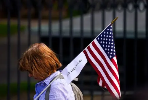 امرأة تحمل علم الولايات المتحدة مع لافتة مكتوب عليها "لا للديكتاتوريين"، تعبر عن موقفها السياسي في تظاهرة.