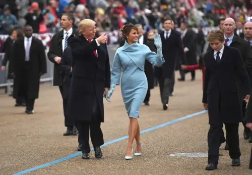 ميلانيا ترامب ترتدي فستانًا أزرق مع بعض التفاصيل الفريدة، وتمشي بجانب دونالد ترامب وسط حشد من المواطنين في حفل تنصيب.