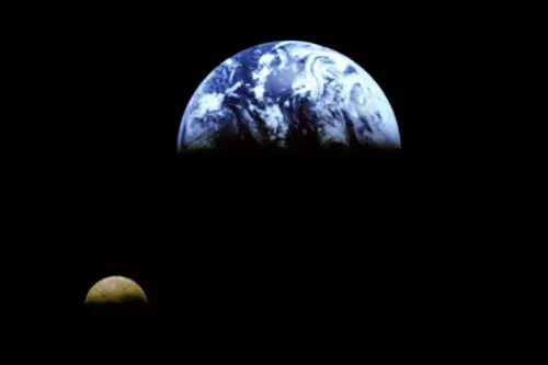 صورة تُظهر كوكب الأرض مع القمر في الفضاء، مع التركيز على تفاصيل السطح المائي والجبلي للأرض. تعكس الصورة موضوع سرعة دوران الأرض وتأثيراتها.