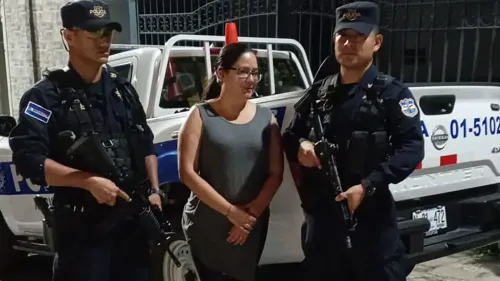 احتجاز المحامية روث إليونورا لوبيز، الناشطة الحقوقية، بين شرطيين مسلحين أمام مركبة للشرطة، في سياق انتقادات للحكومة السلفادورية.