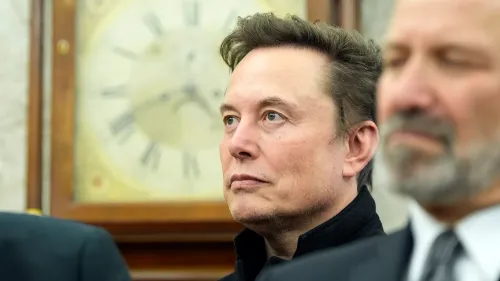 إيلون ماسك يستمع بجدية خلال حدث رسمي، مع وجود ساعة قديمة في الخلفية، مع التركيز على أهمية تحديث نظام مراقبة الحركة الجوية.