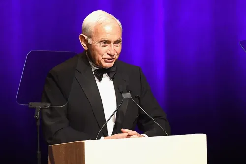 نائب جمهوري يتحدث في حدث رسمي، مع خلفية مضيئة، حيث يسلط الضوء على قضايا تتعلق بالتحقيقات في الاتجار بالجنس.