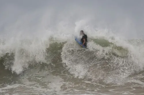 راكب أمواج يتزلج على موجة كبيرة، حيث تظهر المياه المتلاطمة وتأثيرات إعصار إيرين على السواحل.