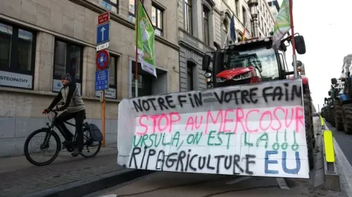 لافتة ضخمة تحمل شعارات احتجاجية ضد اتفاقية ميركوسور، مع وجود جرار زراعي في الخلفية، في بروكسل.