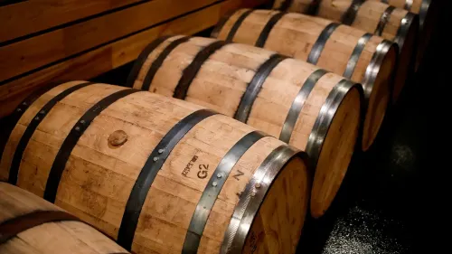 براميل خشبية مرتبة في صف، تمثل تخزين الويسكي الأمريكي، وسط توقعات بفرض رسوم جمركية أعلى من الاتحاد الأوروبي.