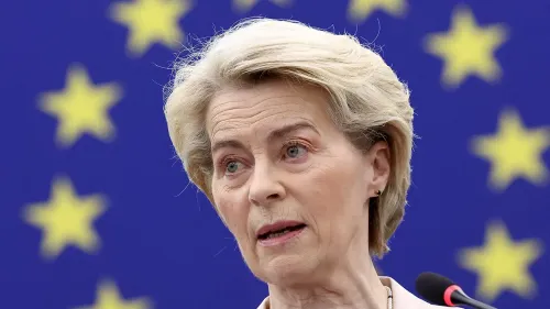 أورسولا فون دير لاين تتحدث في مؤتمر صحفي حول تأثير الرسوم الجمركية الأمريكية على الاقتصاد العالمي، مع خلفية علم الاتحاد الأوروبي.