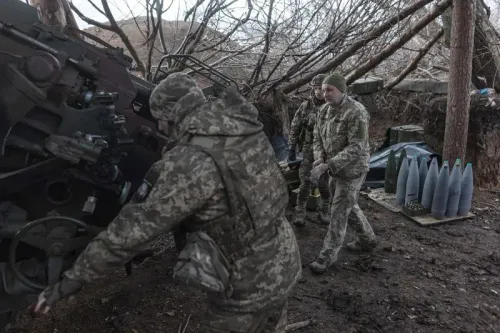 جنود أوكرانيون في موقع عسكري، يعملون على تجهيز مدفعية، بينما تظهر قذائف في الخلفية. تعكس الصورة التحديات اللوجستية في الصراع المستمر.