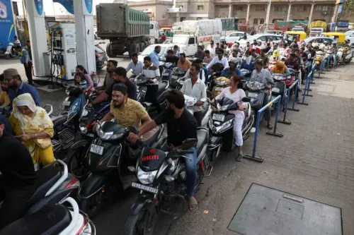 طابور طويل من الناس على دراجاتهم النارية ينتظرون التزود بالوقود في محطة بنزين، يعكس تأثير أزمات الطاقة وارتفاع أسعار الوقود.