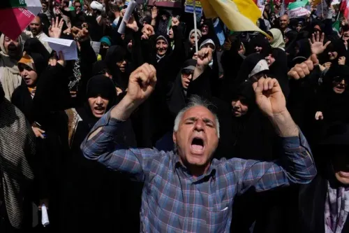 محتجون إيرانيون يرفعون الأعلام ويهتفون بشعارات قوية ضد الهجمات الأمريكية على المنشآت النووية، معبرين عن الغضب والتضامن.