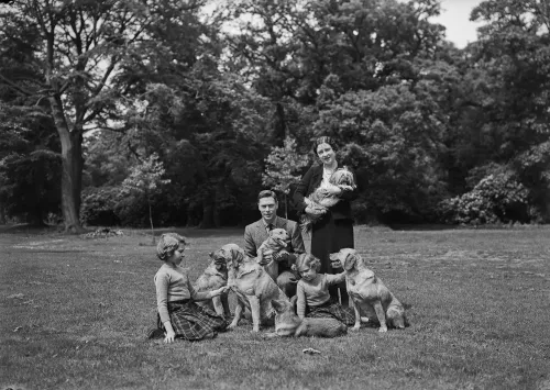 عائلة تتجمع في حديقة واسعة، مع وجود عدة كلاب، في صورة تاريخية تعكس الحياة الملكية في رويال لودج.