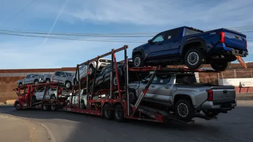 شاحنة نقل تحمل سيارات جديدة تتجه نحو الولايات المتحدة، تزامناً مع الأحاديث عن تأثر الاقتصاد بالتعريفات الجمركية.