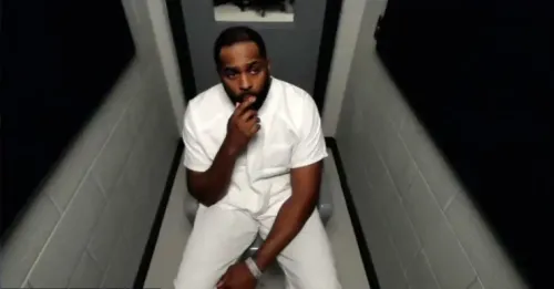 مدرب كرة القدم المُقال شيرون مور يجلس في قاعة المحكمة مرتديًا ملابس السجن البيضاء، معبرًا عن حالة من التوتر بعد اتهامه بارتكاب جنح وجنايات.