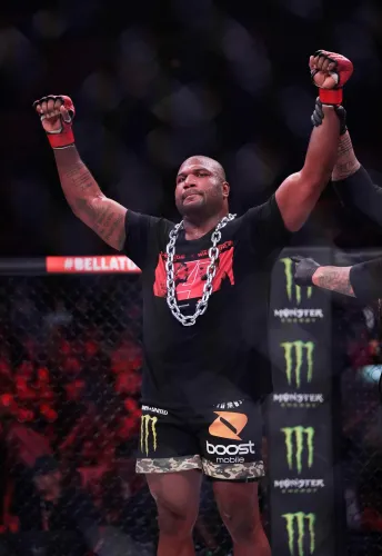 راجا جاكسون، مقاتل فنون القتال المختلطة، يرفع يديه في علامة الانتصار بعد نزال، وسط حلبة مليئة بالمعجبين.