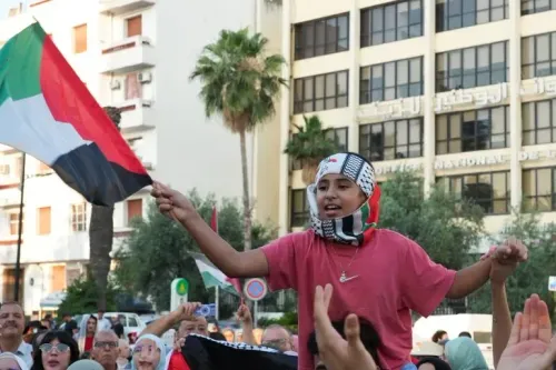 طفل يحمل علم فلسطين ويشارك في مسيرة دعم لغزة، محاطًا بالمتظاهرين الذين يعبرون عن تضامنهم مع القضية الفلسطينية.