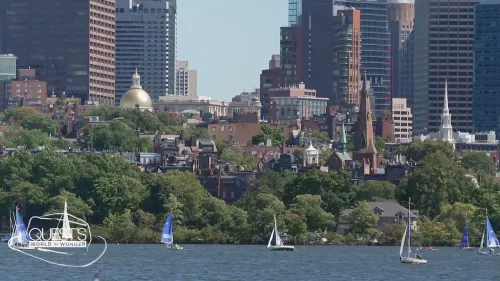مشهد لمدينة بوسطن مع الأبنية الحديثة والأشجار على ضفاف الماء، ويظهر القوارب الشراعية تبحر في النهر.
