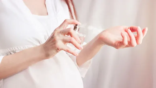 امرأة حامل تستخدم عطرًا، مما يشير إلى التعرض للفثالات، وهي مواد كيميائية مرتبطة بمشاكل النمو العصبي لدى الرضع.
