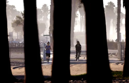 صورة لراكض وراكب دراجة في حديقة تحت أشعة الشمس الساطعة، مع تلميحات لموجة حر قادمة تؤثر على المناطق الغربية من الولايات المتحدة.