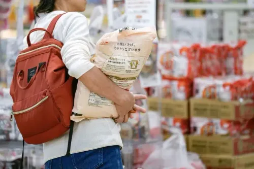 شخص يحمل كيسًا من الأرز في متجر، مما يعكس تأثير ارتفاع أسعار المواد الغذائية نتيجة تغير المناخ.