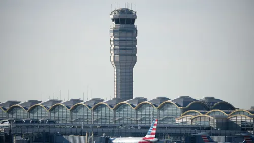 برج المراقبة في مطار رونالد ريغان واشنطن الوطني، مع طائرات متوقفة في المقدمة، يرمز إلى التحديات الحالية في إدارة الحركة الجوية.