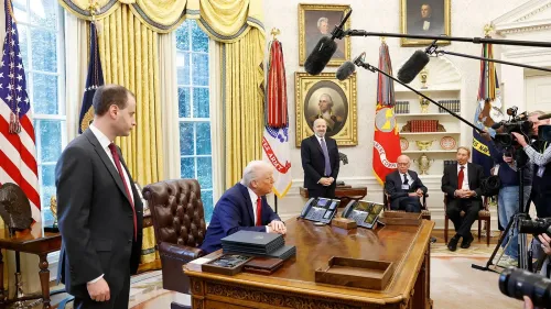 ترامب يجلس في المكتب البيضاوي خلال مؤتمر صحفي، محاطًا بمستشارين وصحفيين، مع التركيز على قضايا التجارة مع كندا.