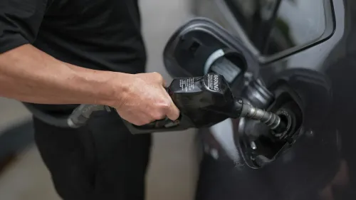 رجل يملأ خزان سيارة بالبنزين في محطة وقود، مع التركيز على مضخة الوقود. تعكس الصورة موضوع ارتفاع أسعار الغاز ومزاعم ترامب.